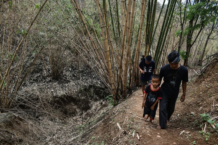 Kang Entri (35) dan anak lelakinya memasuki hutan tutupan di Gunung Puncak Salam di wilayah Kampung Adat Cireundeu, Kelurahan Lewigajah, Kecamatan Cimahi Selatan, Kota Cimahi. Tampak dedaunan dan pepohonan kering akibat kemarau panjang dan kebakaran hutan.