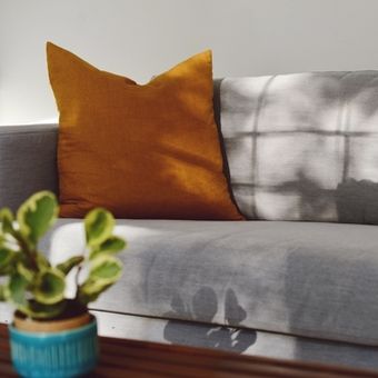 Ilustrasi sofa abu-abu dengan bantal berwarna kuning mustard