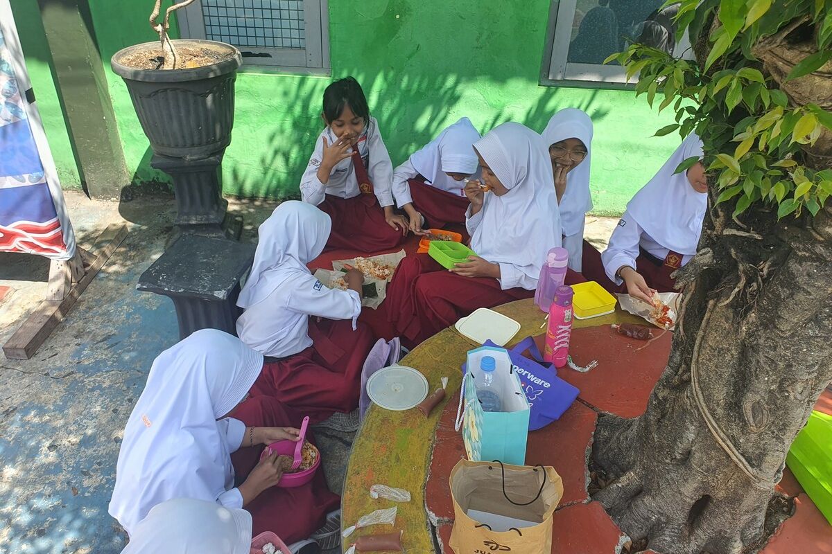 Siswa SD N 1 Wonosari menikmati bekal di bawah pohon di sekolahnya, Senin (13/10/2025)