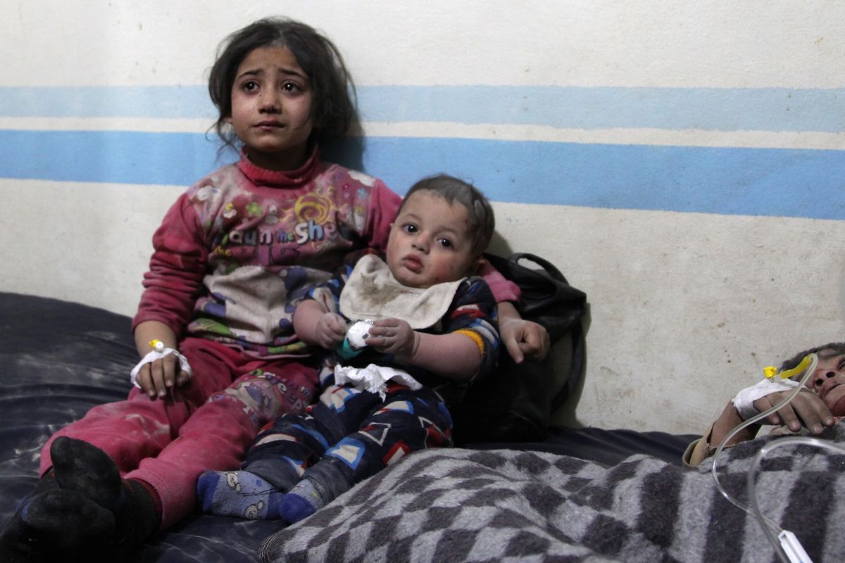 Seorang anak perempuan tengah menggendong bayi dengan di sebelah mereka, terbaring bocah laki-laki yang terluka setelah serangan udara di Idlib, Suriah, pada 11 Februari 2020.