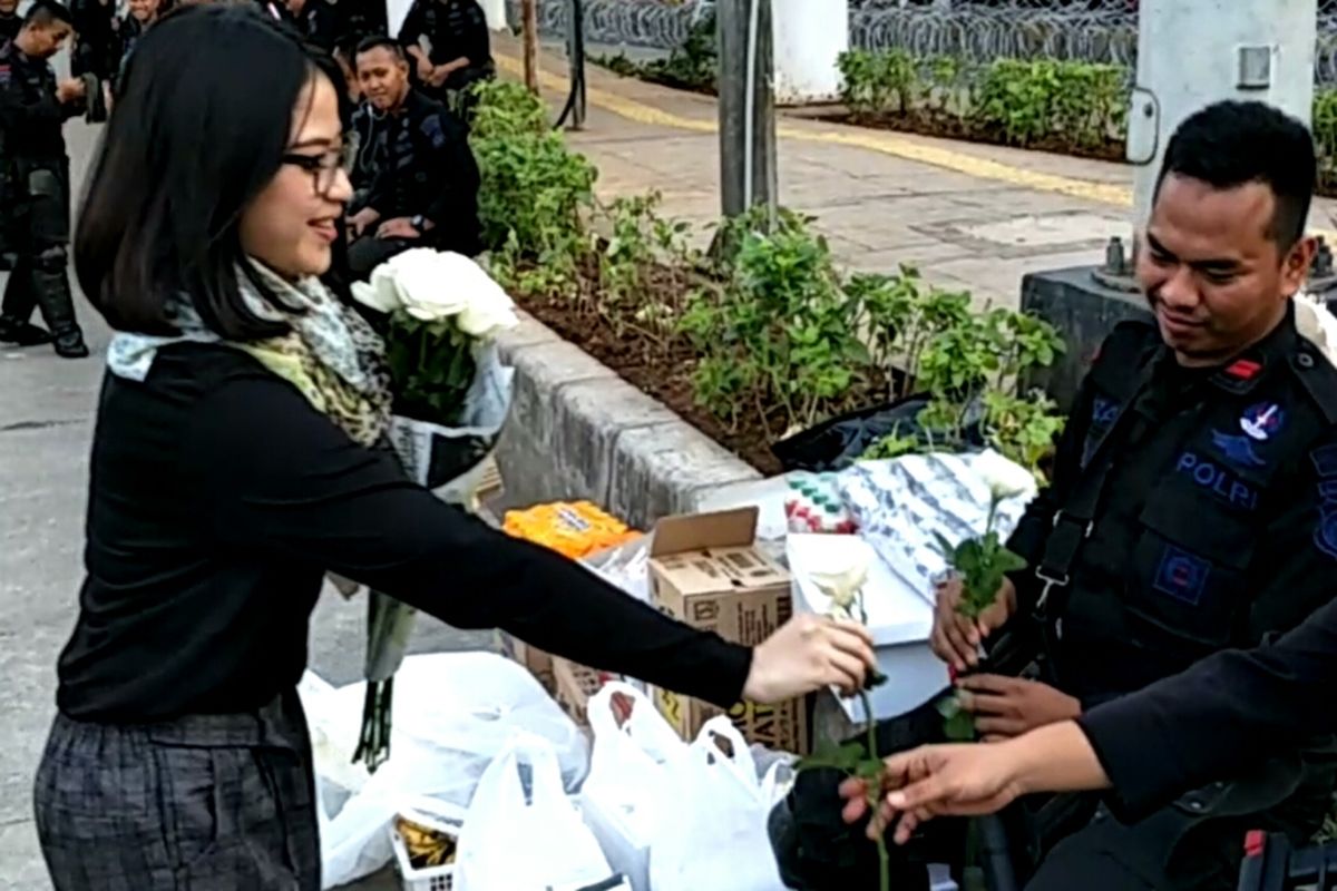 Tampak seorang mahasiswa membagikan bunga mawar putih kepasa seorang personel Brimob yang siaga di sekitar Kantor Bawaslu RI, Jalan MH. Thamrin, Jakarta Pusat, Kamis (23/5/2019).