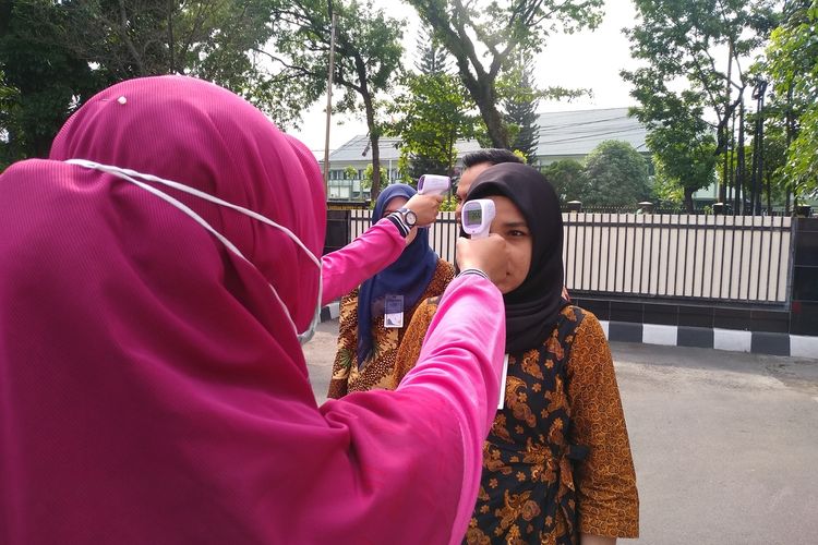 Ilustrasi: Seorang pengunjung diperiksa suhu tubuhnya saat tiba di halaman PTPN IV, Medan, Jumat (6/3/2020).