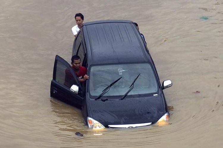 Caption : Luapan Kali Ciliwung memutus jalur kendaraan di Jalan KH Abdullah Syafiie, Tebet, Jakarta Selatan, Senin (13/1/2014). Luapan kali mulai menggenangi permukiman dan memutus jalan sejak Senin dini hari. KOMPAS/AGUS SUSANTO 