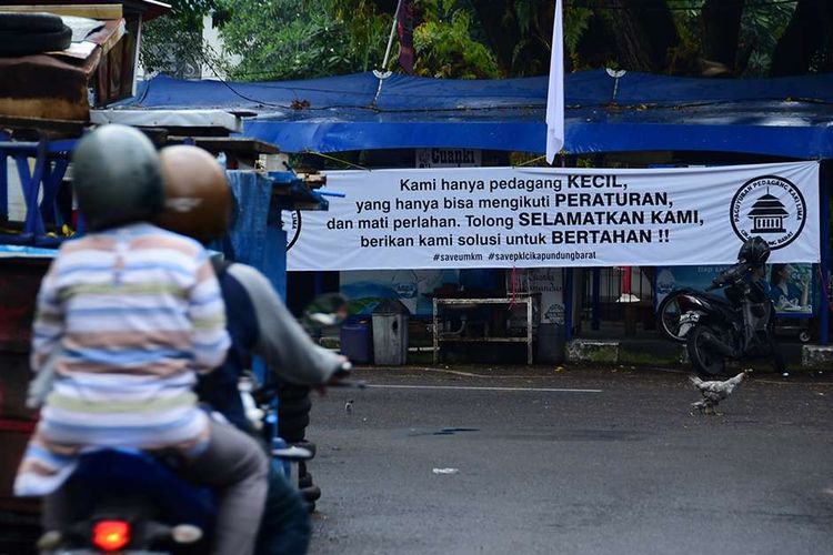 Pedagang kaki lima (PKL) yang berada di Jalan Cikapundung Barat, Kota Bandung, Jawa Barat, melakukan aksi pasang bendera putih di kios mereka, menyusul pemberlakuan PPKM Darurat, Senin (19/7/2021). Bendera putih yang dikibarkan 104 pedagang itu merupakan tanda mereka tak lagi sanggup menghadapi Covid-19 yang telah menghancurkan perekonomian.