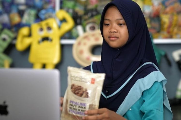 Nina Azzahra memegang sekantong campuran kacang praline President's Choice dari Kanada yang ia temukan di lingkungannya di Indonesia. Aktivis muda itu ingin Kanada menghentikan pengiriman sampah ke negaranya. 
