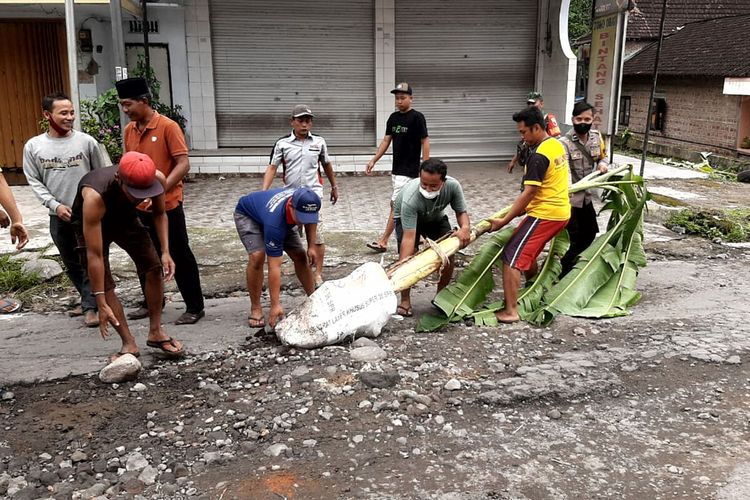 Anggota polisi, TNI dan warga mencabut pohon pisang yang ditanam warga di ruas jalan rusak di Desa Dayu, Kecamatan Nglegok, Kabupaten Blitar, Jawa Timur, Jumat (11/2/2022)