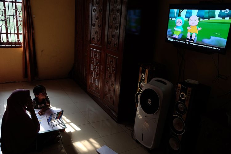 Seorang anak didampingi ibunya belajar dengan melihat tayangan siaran TVRI di rumah mereka, di Deli Serdang, Sumatera Utara, Senin (13/4/2020). Kementerian Pendidikan dan Kebudayaan bekerja sama dengan lembaga penyiaran publik TVRI sejak Senin (13/4) hingga tiga bulan ke depan menyiarkan program belajar bagi siswa mulai dari tingkat pendidikan anak usia dini (PAUD) hingga SMA guna membantu para siswa belajar di rumah selama wabah COVID-19.