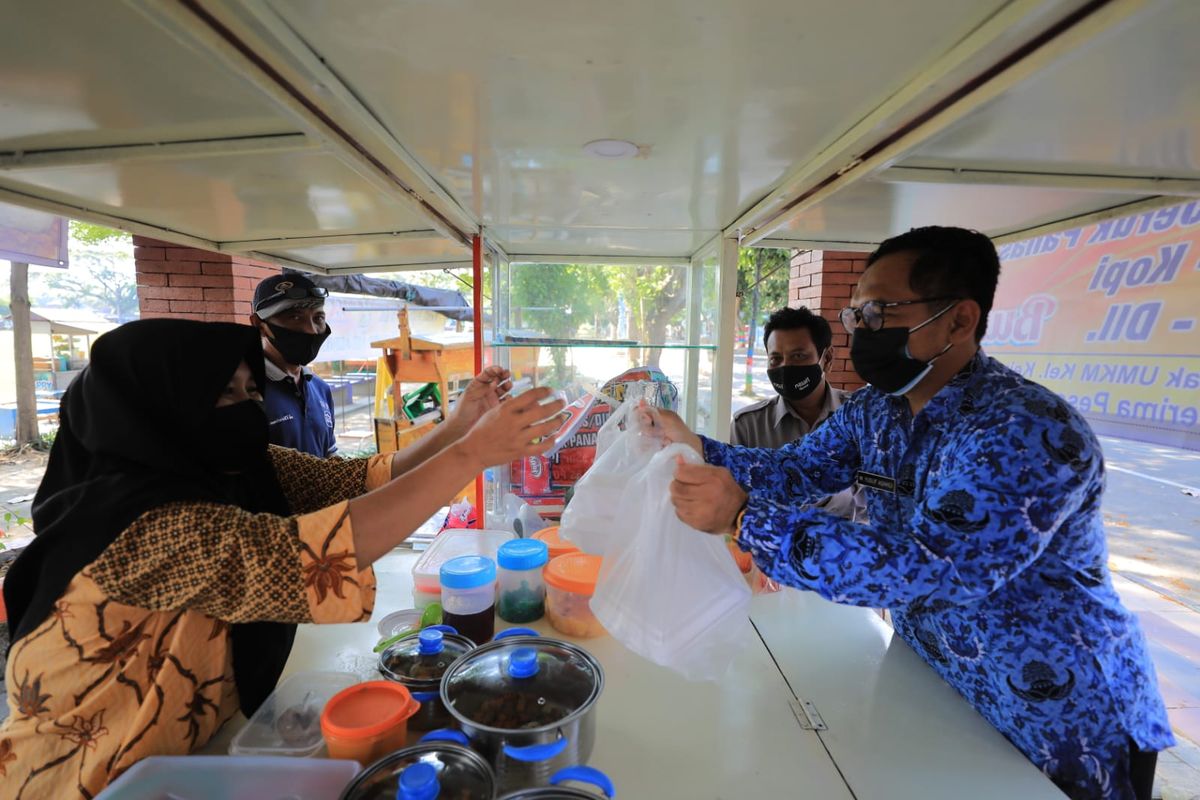 Seorang aparatur sipil negara (ASN) Pemkot Madiun belanja makanan di salah satu pedagang kaki lima. Walikota Madiun, Maidi mewajibkan ASN Pemkot Madiun belanjan kebutuhan harian ke UMKM  atau toko terdekat selama PPKM Darurat.

