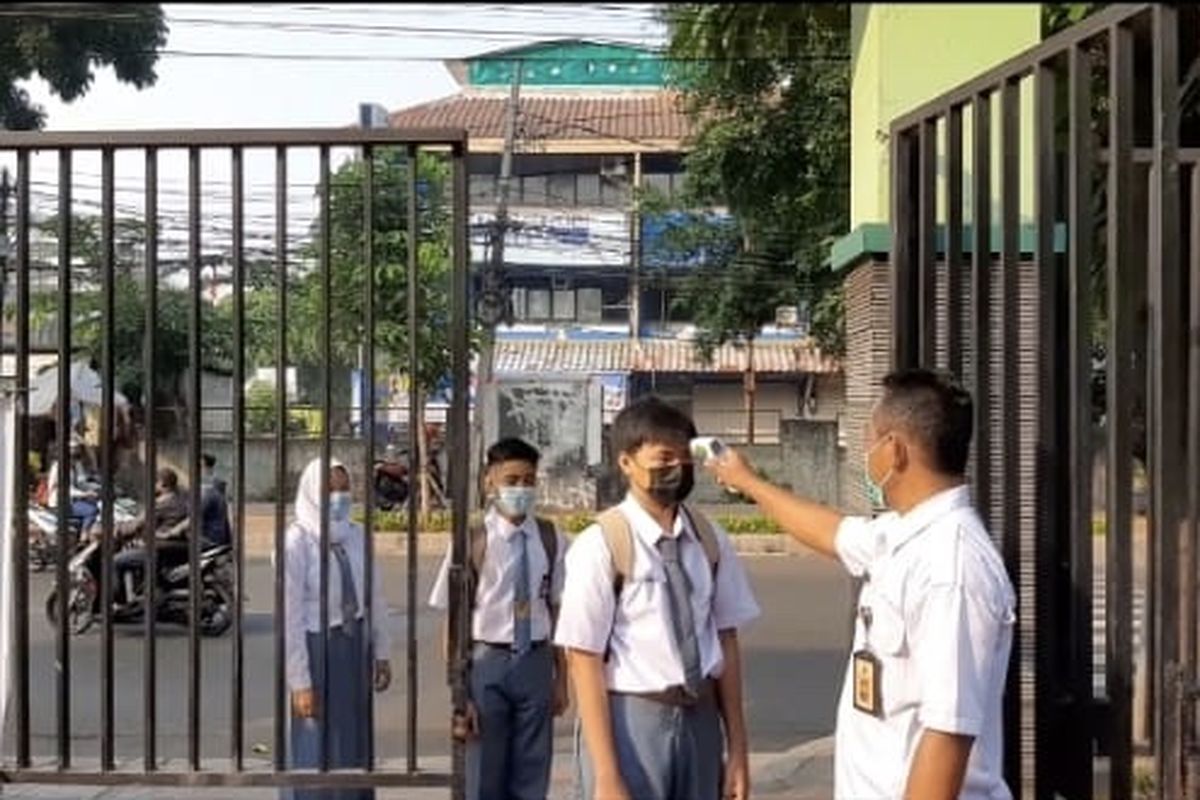 Sejumlah siswa menjalani cek suhu di pintu gerbang SMKN 32 Tebet, Jakarta Selatan pada hari pertama Pembelajaran Tatap Muka (PTM) Terbatas, Senin (30/8/2021) pagi.