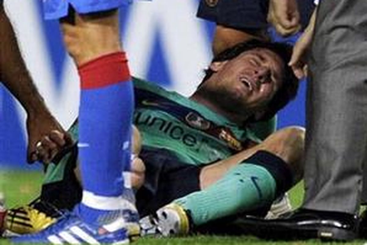 Penyerang Barcelona Lionel Messi mengerang kesakitan seusai mendapatkan tekel keras dari bek Atletico Madrid Tomasz Ujfalusi. 