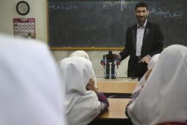 Akbar Rezaei (27) membawa robot ciptaannya saat mengajar di ruang kelas, di sebuah sekolah di dekat Teheran, Iran.
