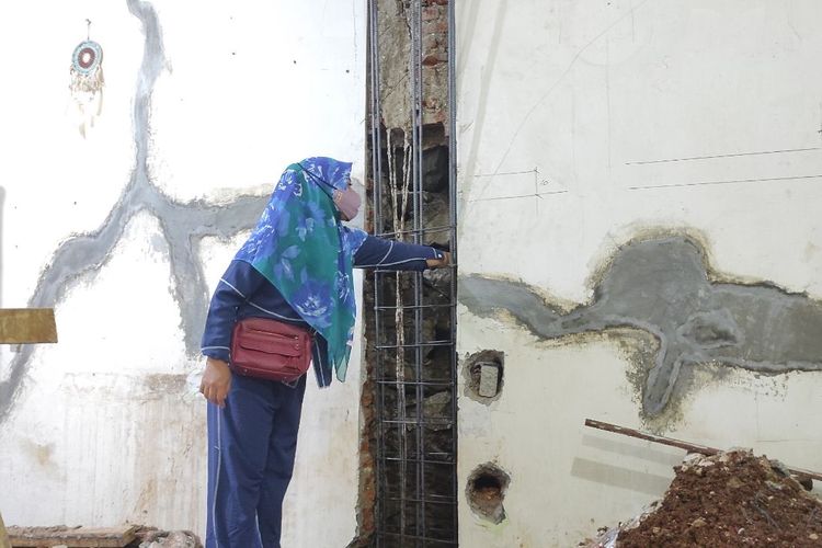 Anak perempuan Ami (53) saat mengambil batu kali dari tembok belakang rumahnya yang dilubangi untuk keperluan renovasi, Senin (15/5/2023). 