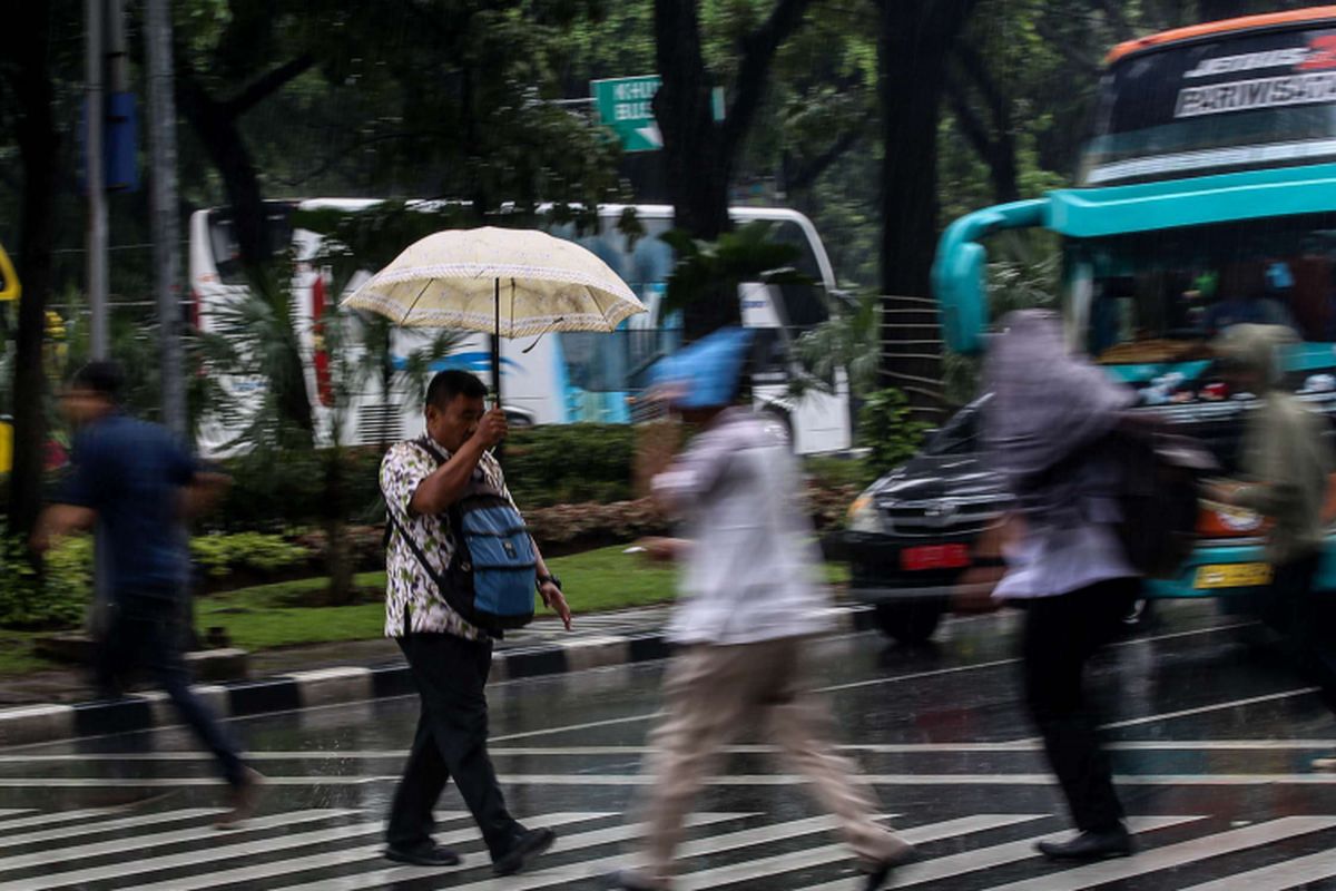 Seorang pria menyebrang zebra cross saat hujan deras di Jalan Medan Merdeka, Jakarta, Jumat (22/2/2019). Badan Meteorologi, Klimatologi, dan Geofisika ( BMKG) memprediksi hujan akan mengguyur wilayah Jabodetabek pada Jumat (22/2/2019) siang.