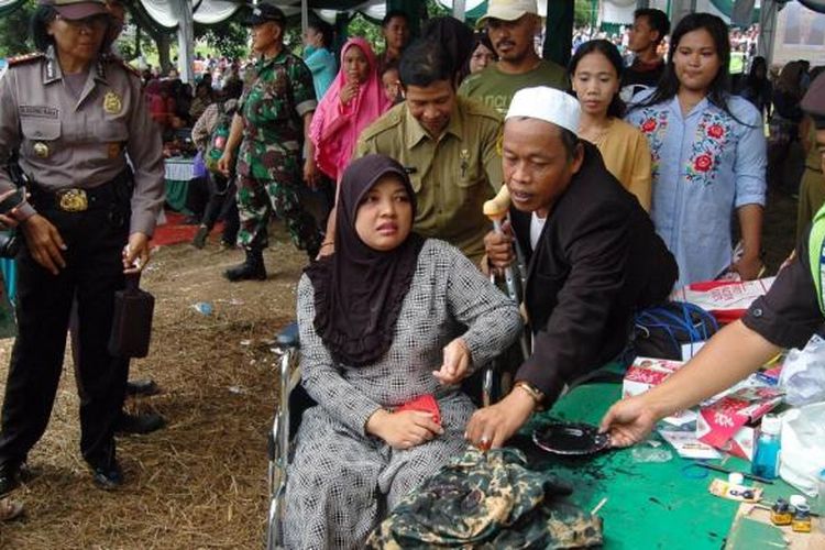 Lilis (36) warga Desa Babakan, Kecamatan Ciseeng, Kabupaten Bogor, datang ke lokasi pemilihan kepala desa sistem e-voting dengan menggunakan kursi roda dan tongkat, Minggu (12/3/2017). Lilis mengalami patah kaki dalam sebuha kecelakaan sepeda motor.