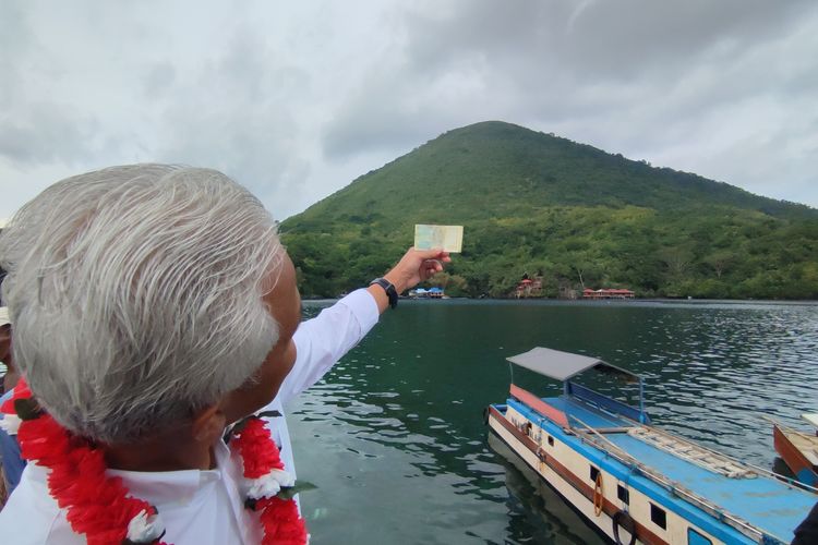Calon presiden nomor urut 3, Ganjar Pranowo, memamerkan uang Rp 1.000 bergambar Gunung Api Banda, tepat di depan Gunung Api Banda, Banda Neira, Selasa (30/1/2024).