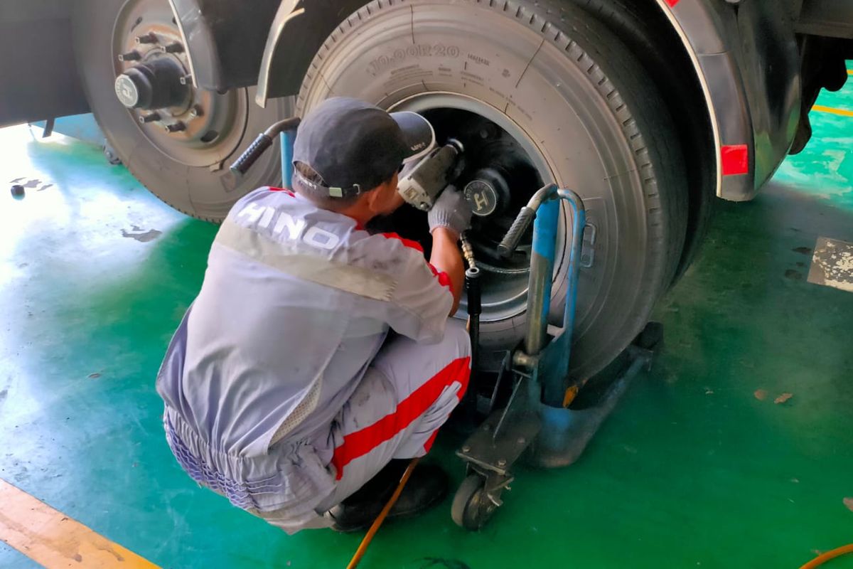 Teknisi Hino sedang memperbaiki ban truk