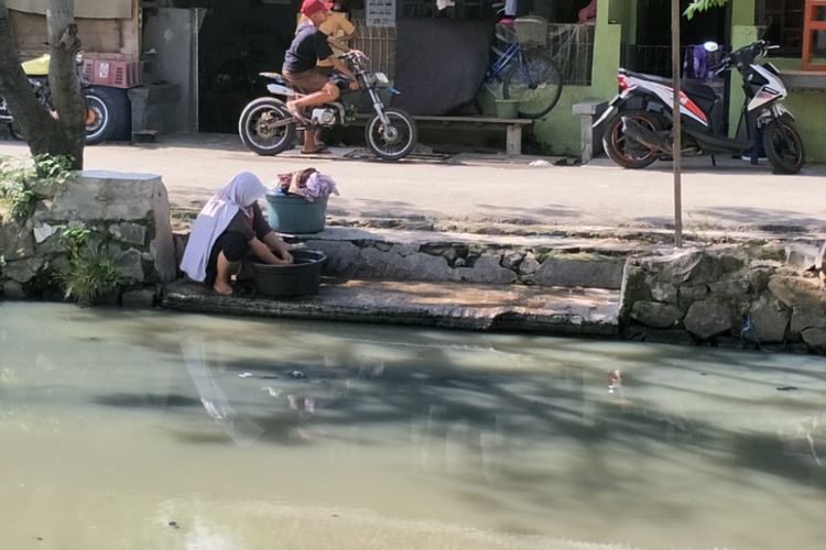 Seorang warga Jalan Jambu Air, Pegadungan, Kalideres, Jakarta Barat tengah mencuci baju di aliran Kali Maja, Rabu (8/11/2017).