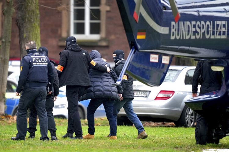 Seorang tersangka dikawal dari helikopter polisi oleh petugas polisi setelah tiba di Karlsruhe, Jerman, Rabu, 7 Desember 2022. Ribuan petugas polisi melakukan penggerebekan di sebagian besar Jerman pada Rabu terhadap tersangka ekstremis sayap kanan yang diduga berusaha untuk menggulingkan pemerintah dalam kudeta bersenjata. Para pejabat mengatakan 25 orang ditahan.