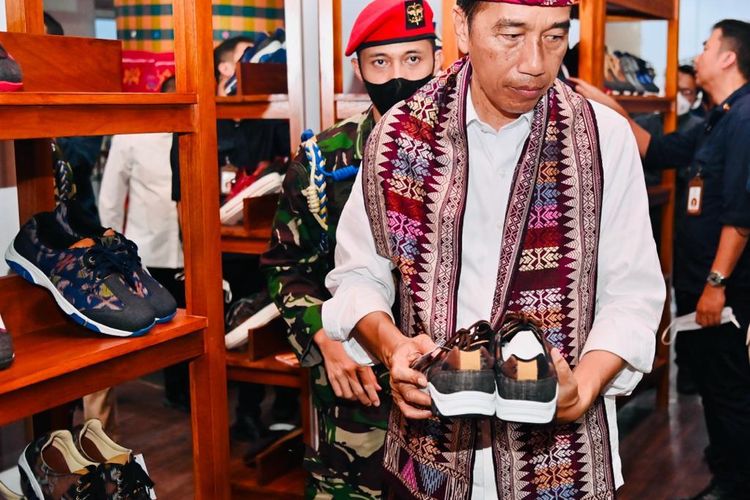 Presiden RI Joko Widodo (Jokowi) berbelanja sepatu kets tenun Bali saat berkunjung ke Sentra Tenun Jembrana, Kabupaten Jembrana, Provinsi Bali, Kamis (2/2/2023).
