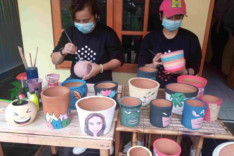 Peni melukis pot terracota bersama adiknya.