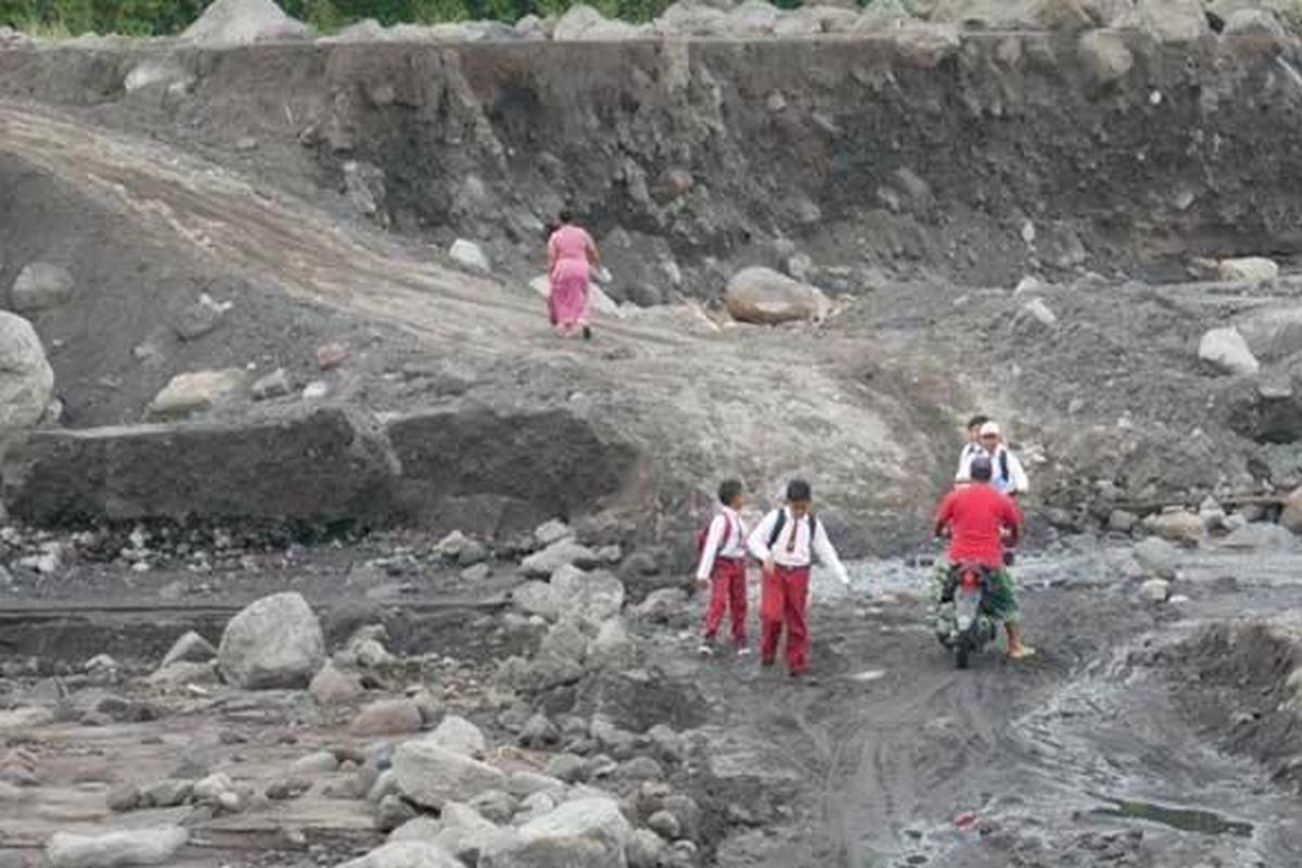 Siswa dan warga melintasi jalur alternatif untuk bisa menyeberangi Sungai Regoyo di Dusun Sumberlangsep, Desa Jugosari, Lumajang, Selasa (25/1/2022)