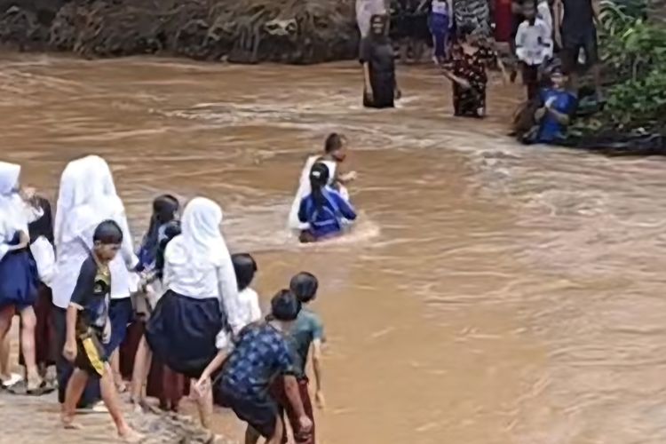 Suasana saat anak sekolah di Kampung Cegog, Desa Rancapinang, Kecamatan Cimanggu, Kabupaten Pandeglang menyeberangi sungai deras akibat jembatan putus, Rabu (22/10/2025).