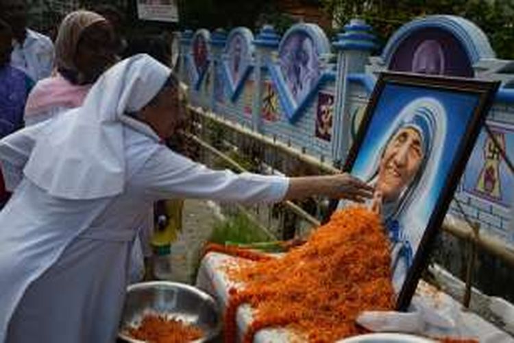 Seorang biarawati Katolik di Siliguri, India menyentuh foto Bunda Teresa yang pada Minggu (4/9/2016), resmi dinobatkan menjadi santa atau orang suci di Vatikan.