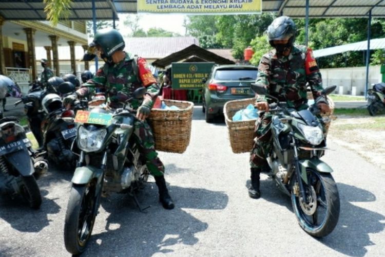 Prajurit TNI AD Korem 031/Wira Bima membawa nasi bungkus untuk dibagikan kepada warga terdampak PPKM Level 4 di Kota Pekanbaru, Riau, Selasa (27/7/2021).