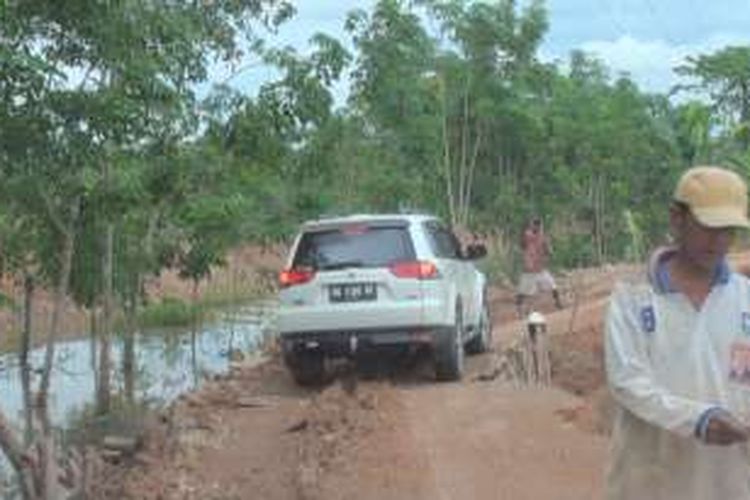 Sebuah kendaraan harus dituntun oleh warga saat melintas di jalan darurat pengganti jalan yang putus di Desa Ulak Kembahang Kecamatan Muara Kuang Ogan Ilir