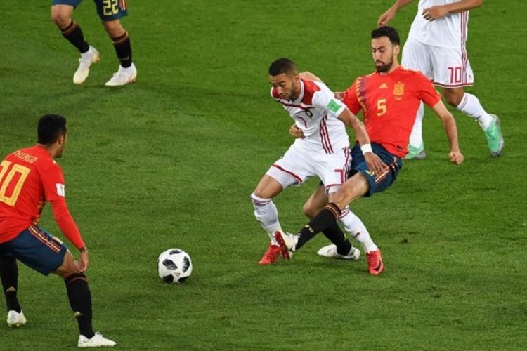 Gelandang Maroko, Hakim Ziyech, dijaga pemain Spanyol, Sergio Busquets, pada pertandingan Grup B Piala Dunia 2018 di Kaliningrad, 25 Juni 2018. 