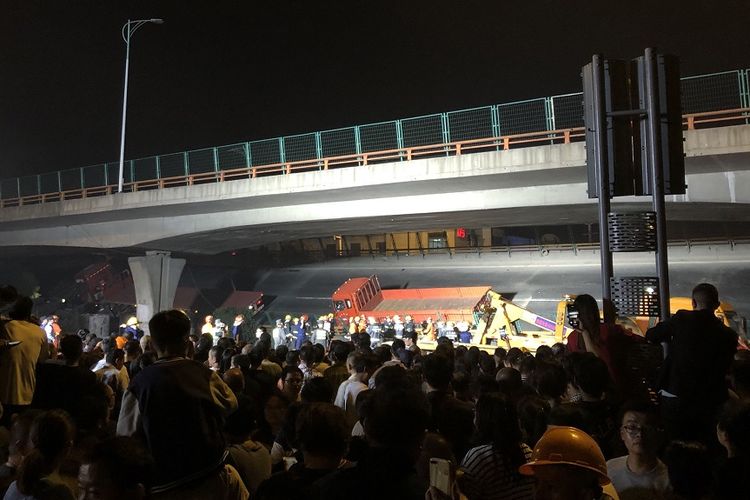 Warga berkerumun di lokasi runtuhnya sebuah jalan layang di kota Wuxi, provinsi Jiangsu, China, pada Kamis (10/10/2019) malam. Tiga kendaraan tertimpa dan tiga orang tewas dalam insiden itu.