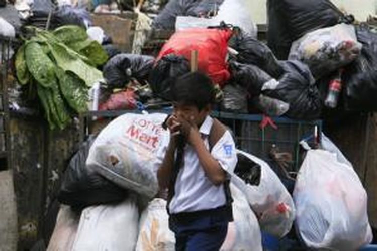 Seorang pelajar menutup hidung saat melintasi gerobak-gerobak sampah yang sudah tiga hari tertahan di Tempat Pembuangan Sampah (TPS) Terpadu Tegallega, Bandung, Jawa Barat, Rabu (15/12/2010). 