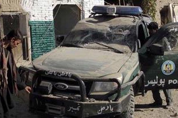 Petugas keamanan memeriksa sebuah mobil polisi yang hancur akibat serangan bom bunuh diri di Kandahar, Kamis (8/11/2012) pagi.