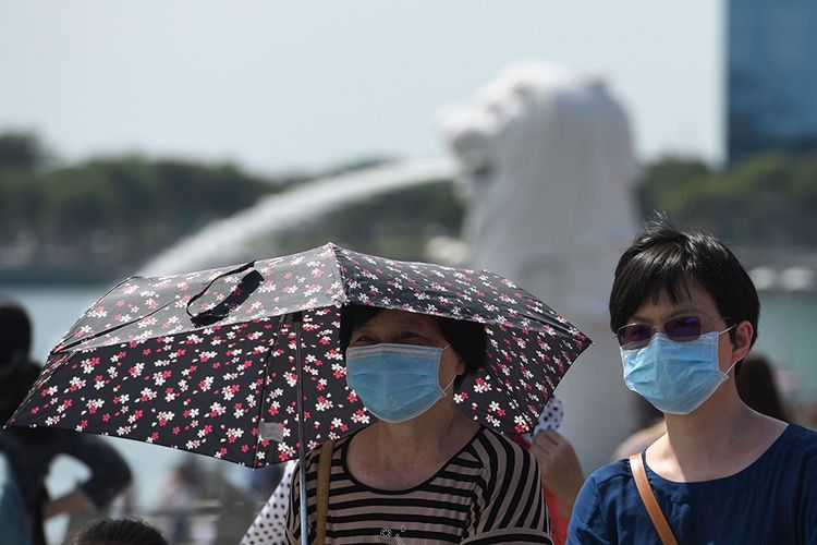 Para pengunjung mengenakan masker pelindung wajah di kawasan Marina Bay di Singapura, Sabtu, (26/1/2020), menyusul temuan warga diduga terinfeksi virus corona di negara itu. Hingga saat ini, sudah 12 negara di berbagai belahan Bumi yang positif mengumumkan terdampak virus corona yang dilaporkan sudah menjangkiti 1.300 orang dan membunuh 41 orang di China.