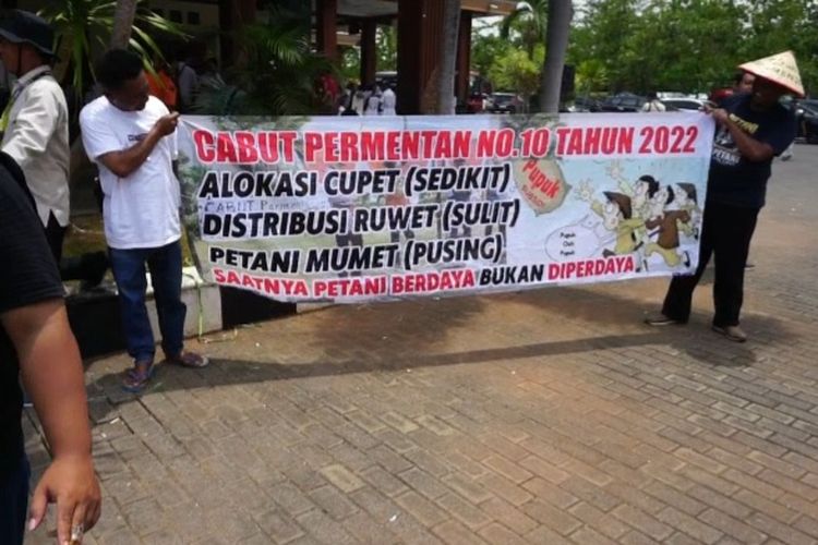 Jumantoro perwakilan Asosiasi Petani Pangan Indonesia membentangkan spanduk meminta Permentan 10 Tahun 2022 dicabut, saat kunjungan Menteri Pertanian Andi Amran Sulaiman ke Kabupaten Tuban, Jawa Timur. Kamis (23/11/2023).