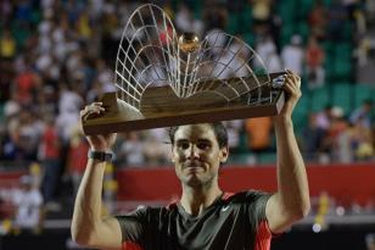Petensi Spanyol Rafael Nadal mengangkat trofi juara Rio Open, setelah memenangi laga final melawan Alexandr Dolgopolov dari Ukraina, di Rio de Janeiro, Brasil, Minggu (23/2/2014). Nadal menang 6-3, 7-6(3).