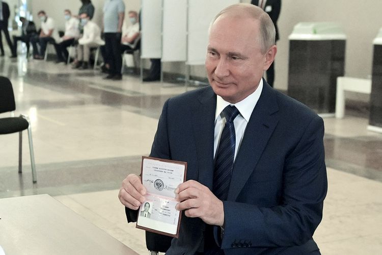 Presiden Rusia Vladimir Putin menunjukkan paspornya kepada anggota komisi pemilihan ketika dia tiba untuk mengambil bagian dalam pemungutan suara di tempat pemungutan suara di Moskwa, Rusia, Rabu, 1 Juli 2020.