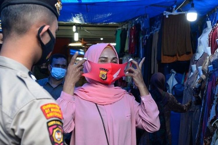 Personil gabungan Polri, TNI dan Satpol PP memberikan masker gratis kepada seorang pedagang saat melakukan pengawasan pusat keramaian di Pasar Aceh, Banda Aceh, Aceh, Kamis (06/05).