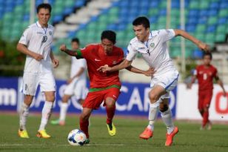 Pemain Indonesia Evan Dimas Darmono mencoba melewati hadangan pemain Uzbekistan Abdullaev Ibrokhim (kanan) pada turnamen sepak bola Piala AFC U-19 di Stadion Thuwunna, Yangon, Myanmar, Jumat (10/10/2014). Indonesia menyerah 1-3. 