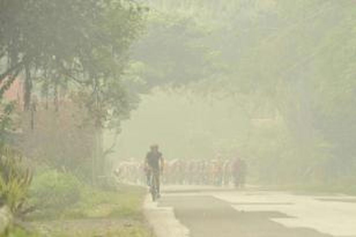 Para pebalap menembus pekatnya kabut asap dalam etape ketiga Tour de Singkarak dari Desa Adat Sijunjung menuju Sport Centre Koto Baru, Sumatera Barat, Senin (5/10/2015). Pada etape ini, para pebalap mengayuh sepeda sejauh 184,5 kilometer.