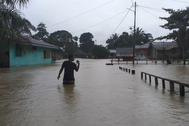 Seorang warga melintasi genangan banjir di Desa Gunung Sahilan, Kecamatan Gunung Sahilan, Kabupaten Kampar, Riau, Rabu (11/12/2019).