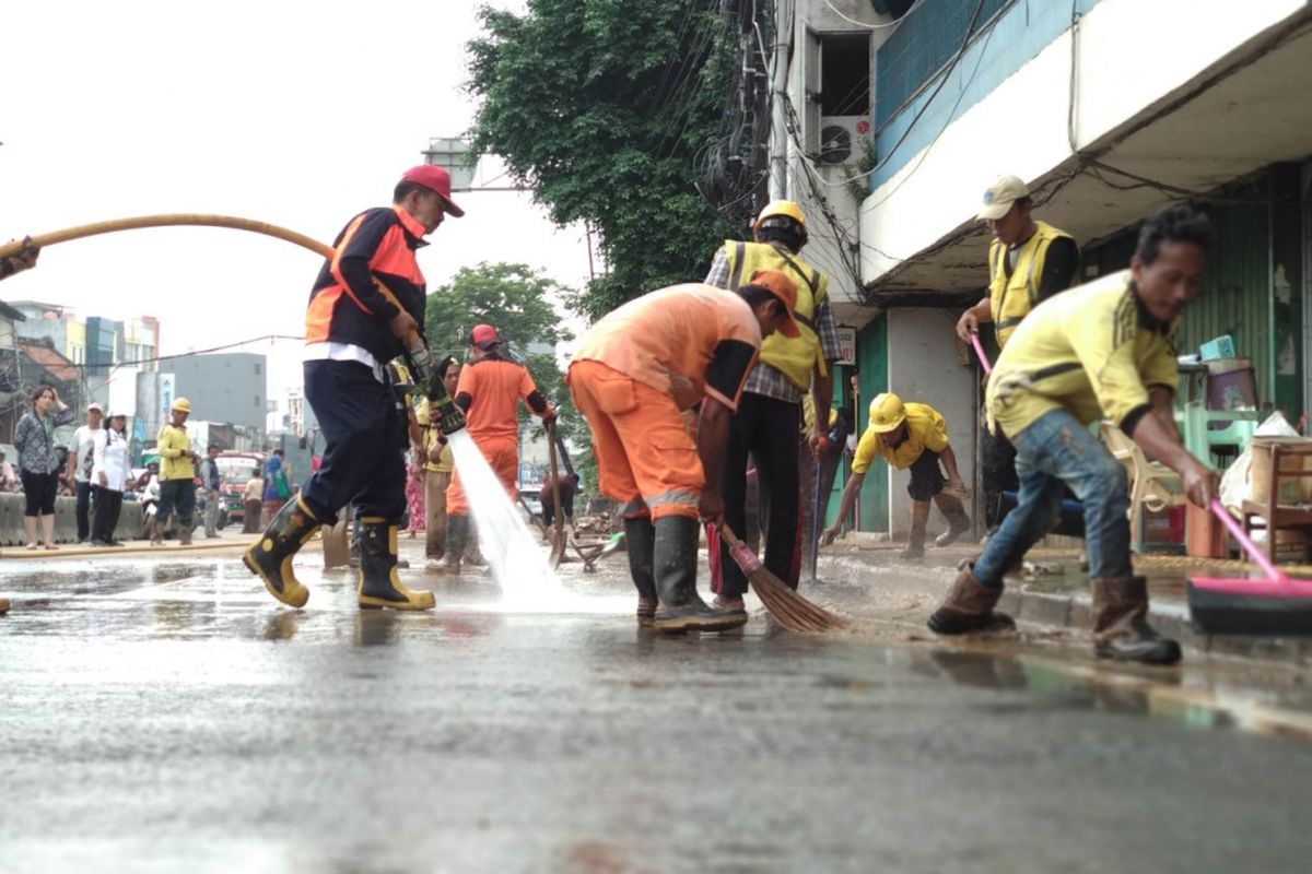 Para petugas membersihkan tumpukan lumpur di jalan Jatinegara, Jakarta Timur, Rabu (7/2/2018)