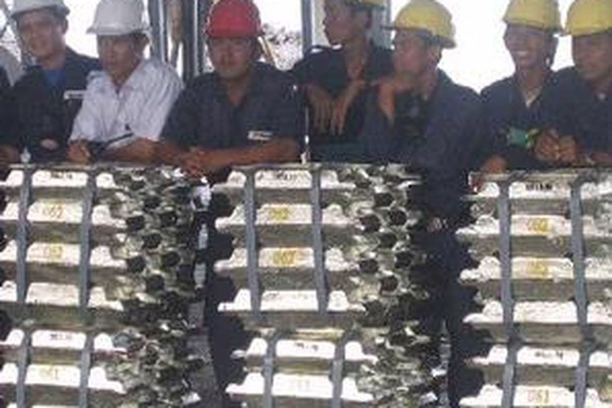Para karyawan PT. Timah Tbk, Kundur tengah berdiri di belakang tumpukan timah produk perusahaan itu.