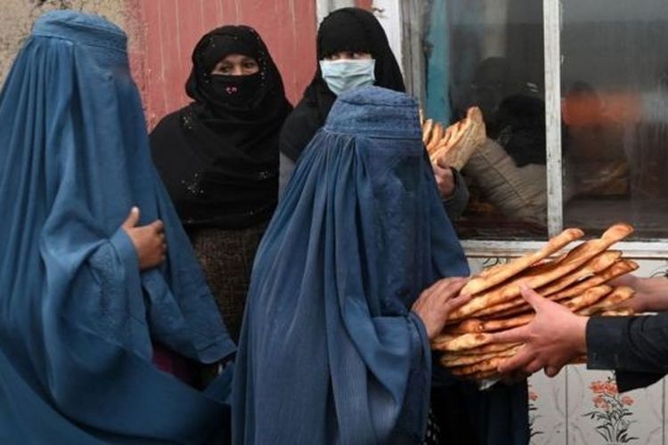 Perempuan Afghanistan yang mengenakan Burqa menerima roti gratis yang didistribusikan sebagai bagian dari kampanye Save Afghans From Hunger.