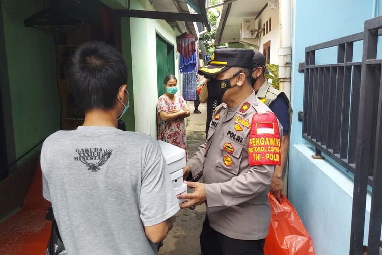 Kapolsek Jagakarsa memberikan bantuan makan siang kepada tiga orang anak yang sedang menjalani isolasi mandiri di Gang Haji Usman, Srengseng Sawah, Jagakarsa, Jakarta Selatan.