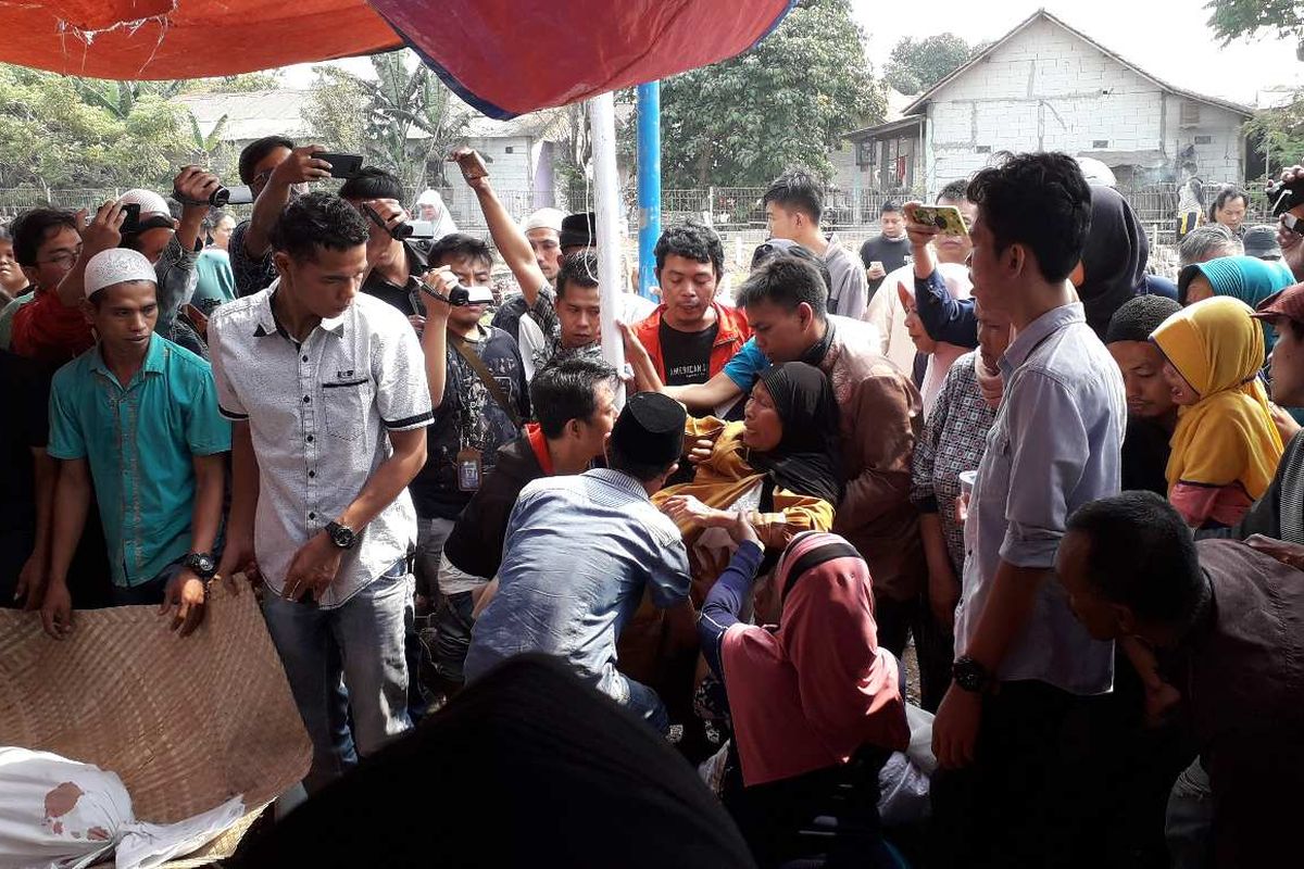 Ibunda Fatmawati, Asnia (berbaju kuning) tak kuasa melihat jenazah ketiga anaknya dimakamkan pada Jumat (2/8/2019) di TPU Selapanjang, Tangerang.