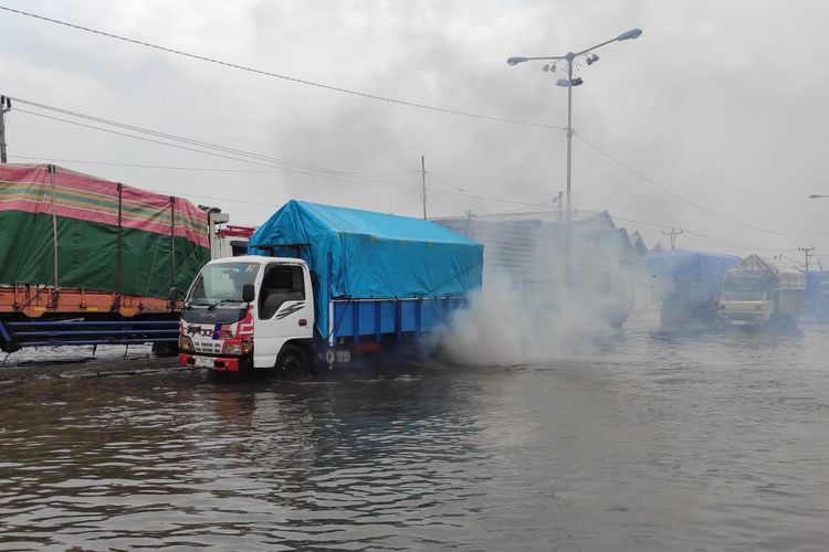 Sebuah truk mengeluarkan asap tebal saat nekat menerjang banjir di Pantura Sayung, Kabupaten Demak, Selasa (28/10/2025). Ada 16 titik banjir di Semarang, ketinggian air 5-60 cm. Modifikasi cuaca oleh BPBD dan BNPB dianggap tidak efektif.