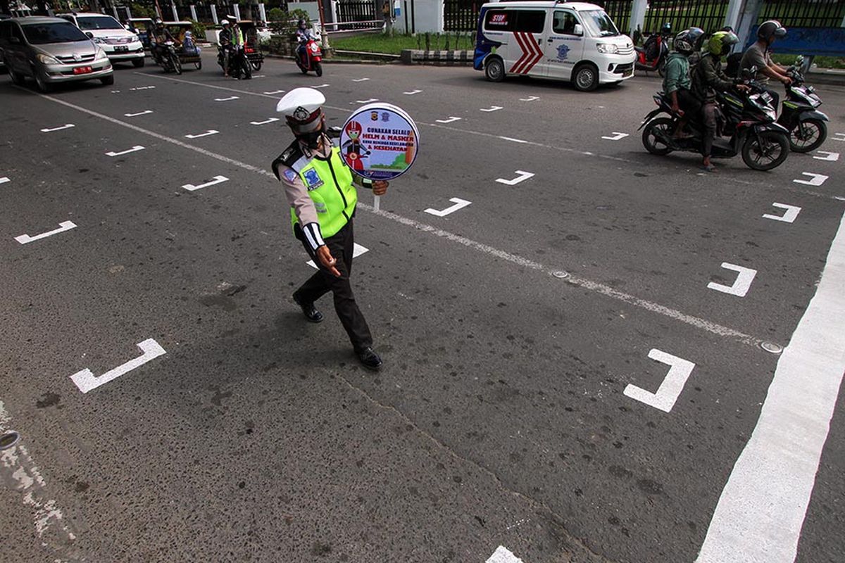 Polisi mengatur pengendara sepeda motor untuk berhenti di belakang garis untuk menjaga jarak antarpengendara saat sosialisasi penerapan jaga jarak di Kota Lhokseumawe, Aceh, Rabu (15/7/2020). Garis tersebut dibuat untuk membatasi jarak antarpengendara di kawasan traffic light guna mencegah penyebaran COVID-19.