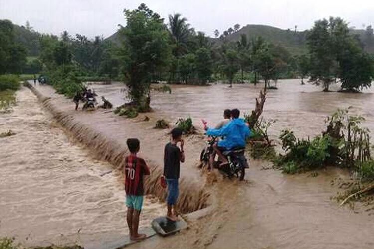 Sejumlah warga nekat menyeberangi jalan yang sudah teredam banjir akibat sungai Bolango meluap. 