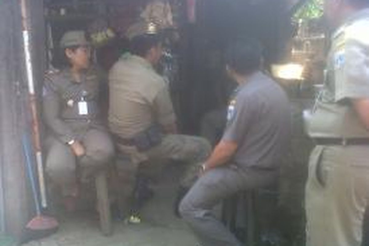 Petugas Satpol PP terlihat duduk-duduk saat penertiban Pasar Gembrong, Jakarta Timur, Rabu (14/8/2013). Sebab, tak ada pedagang yang menggelar lapak di badan jalan.